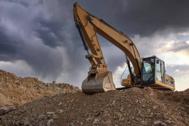 Toprağı ve kumu hareket ettiren bir inşaat alanında kazıcı.