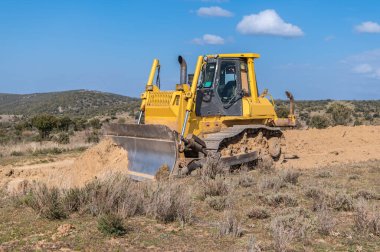 Kazıcı inşaat alanında toprak ve kum taşıyor.