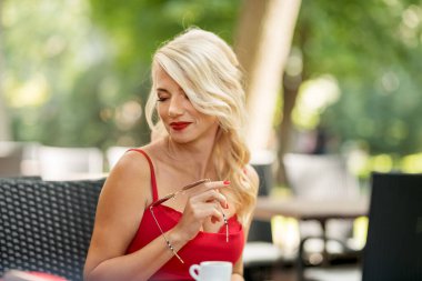 Caddedeki kafede kırmızı elbiseli, kendine güvenen bir kadının portresi..