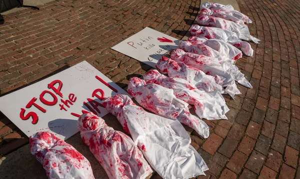 Boston, ABD - 08 Nisan 2022. Ukrayna 'da ölen çocukların anısına, Ukrayna' yı desteklemek için eylem. Bebeklerin kanlı bezlerle yerleştirilmesi ve bir afiş 