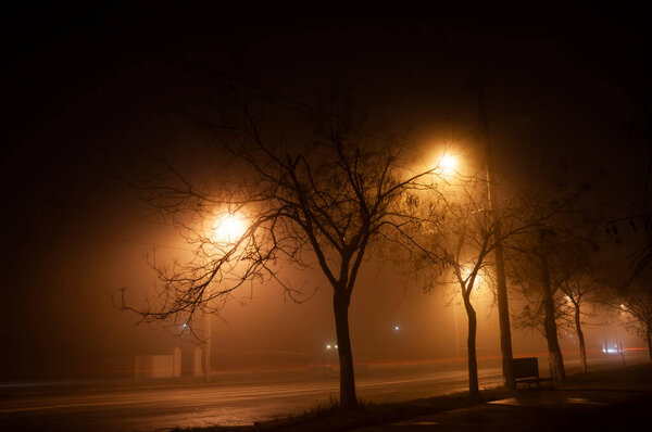 Ночью пустынная улица в густом тумане. размытые огни проезжающих машин.