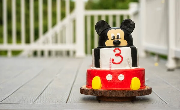 Homemade children's bright cake with a muzzle of a mouse. Celebrating the birthday of a 3 year old child.