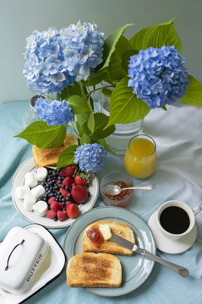 Cute breakfast with fruits and coffee in the garden, blue hydrangea flowers.