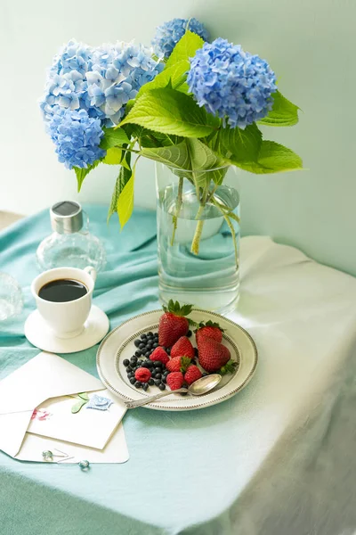Cute breakfast with fruits and coffee in the garden, blue hydrangea flowers.