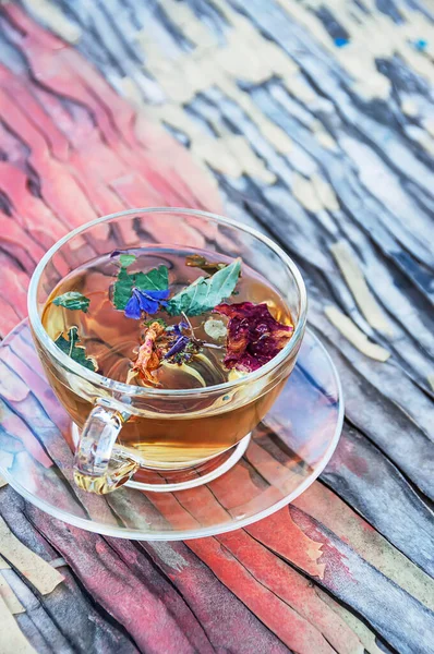 Cup with herbal tea on wooden cracked colored background.