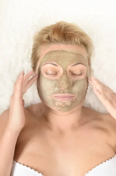 Girl\'s face with a cosmetic face mask. Home or salon care.