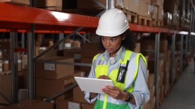 Tabletli bir kadın depoda envanter tutuyor.