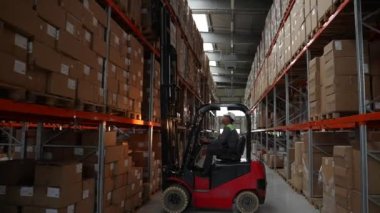Erkek çalışan fabrika deposunda yükleyici üzerinde çalışıyor.