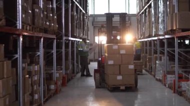 Forklift sürücüsü depodaki kutuları kaldırıyor.