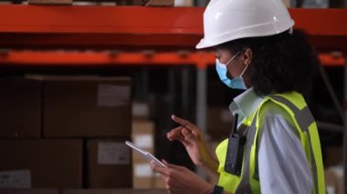 Envanter sırasında yüz maskesi takan depo yöneticisi