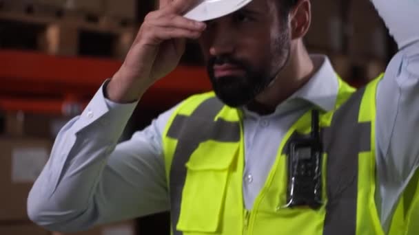 Selbstbewusster Mann Lagerarbeiter setzt harten Hut auf — Stockvideo
