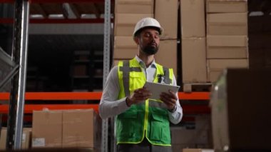 Tabletli bir depo çalışanı envanter çıkarıyor.