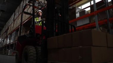Forklift 'teki depo işçisi malları kutularda taşıyor.