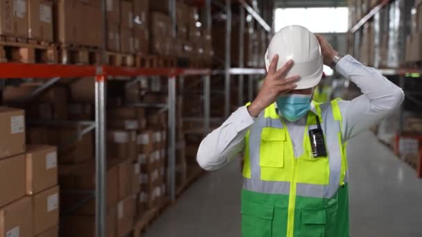 Уверенный мужчина надевает каску на складе — стоковое видео
