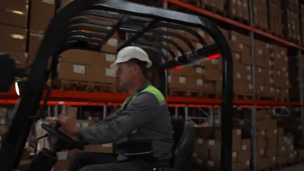 Férfi munkás targoncát vezet a raktár körül — Stock videók