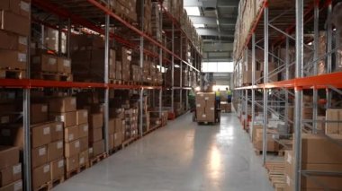 Forklift kutuları depodaki raflara yüklüyor.