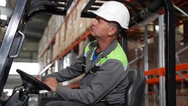 Autista di carrelli elevatori in cappello rigido durante il lavoro in magazzino — Video Stock