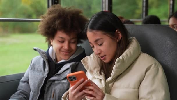 Estudantes multinacionais usando telefone no ônibus escolar — Vídeo de Stock