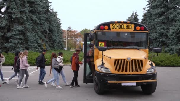 Wielorasowi uczniowie na zmianę wchodzą do autobusu szkolnego — Wideo stockowe