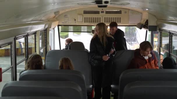 Estudantes diversos entrando no ônibus escolar após o estudo — Vídeo de Stock