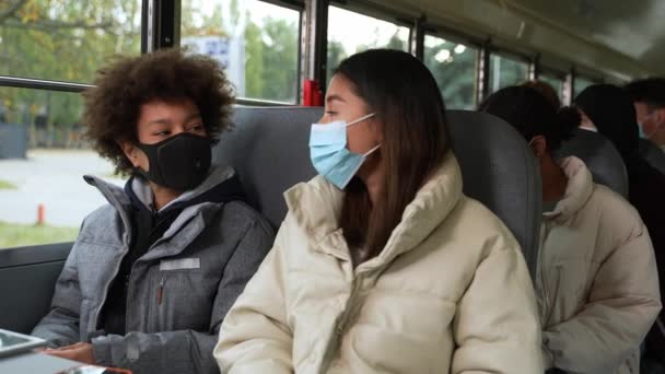 Diversos alumnos enmascarados que se comunican en autobús escolar — Vídeo de stock