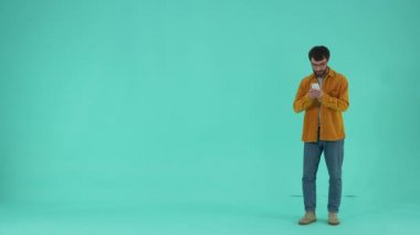 Odaklanmış sakallı adam piyango sonuçlarını beklerken cep telefonu ekranına bakıyor. Kazanan çığlık çığlığa evet işareti yapıyor. Şanslı adam piyangoda başarı gösteriyor.