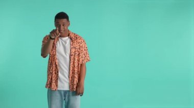 Pozitif afro-amerikalı adam selam veriyor ve önünde parmağını sallıyor. Bu arada büyük tekliflere dikkat etmesi ve satın alma, reklam, promosyon yapması için jestlerle seyirciyi davet ediyor.