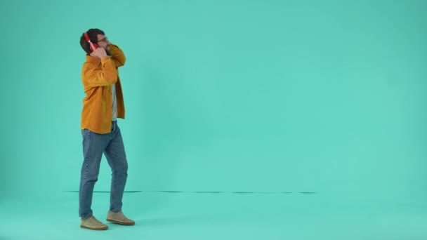 Gözlüklü Neşeli Adam Kulaklıkla Müzik Dinliyor Mavi Stüdyo Arka Planında — Stok video