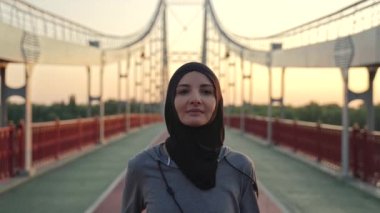 Çekici, fit, tesettürlü Müslüman bir kadın sabahları antrenmanların keyfini çıkarıyor. Şehir köprüsünde açık hava kardiyo eğitimi sırasında spor Arap koşucusu, aktif sağlıklı yaşam tarzı konsepti