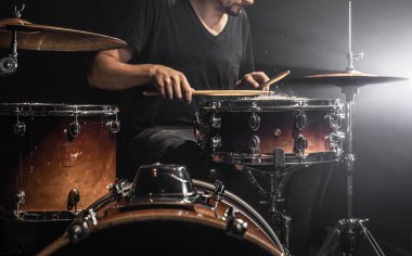 Bir erkek davulcu, karanlık bir odada davul çalar..