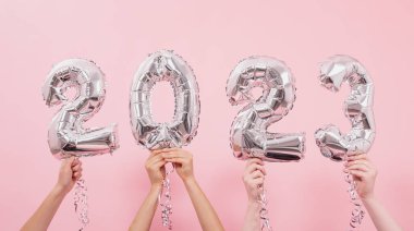 Mutlu yıllar 2023 kutlamaları. Gümüş folyo balonları. Pembe arka planda 2023 numara..