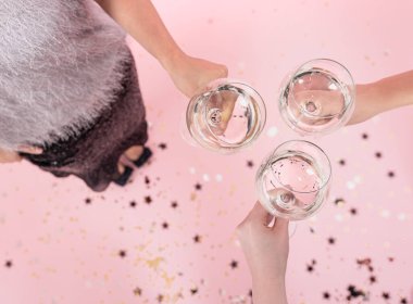 Pembe arka planda kızların elinde şampanya kadehleri, kopyalama alanı..