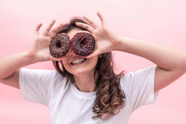 Ellerinde donutlar, ellerinde gülücükler, ellerinde pembe çörekler, ellerinde pembe bir arka plan..