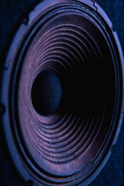 Siyah arkaplanda renkli ışıklandırmalı hoparlör zarının yakın plan görüntüsü.