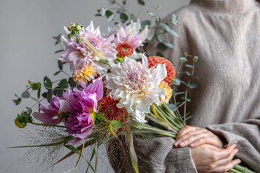 Kadın ellerinde kasımpatı çiçekleri olan parlak bir çiçek buketi, parlak çiçek aranjmanı..