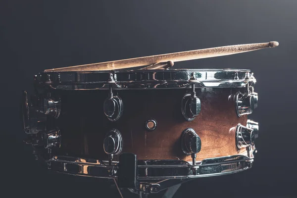 Close-up, snare drum, percussion instrument against a dark background with stage lighting.