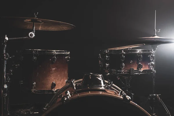 Drums, bass drum, hi-hat, cymbals on a dark background with beams from a spotlight, copy space.