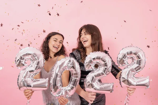 两个粉红背景的快乐女孩拿着编号2022的银箔气球 — 图库照片