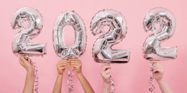 Mutlu yıllar 2022 kutlamaları. Gümüş folyo balonları. Pembe arka planda 2022 numara..