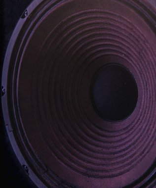 Siyah arkaplanda renkli ışıklandırmalı hoparlör zarının yakın plan görüntüsü.