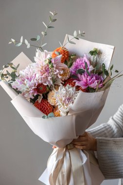 Kadın ellerinde kasımpatı çiçekleri olan büyük, şenlikli bir buket çiçek düzenleme konsepti..
