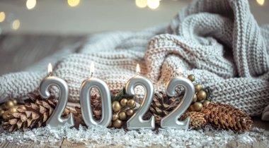 Noel arkaplanı, 2022 sayıları şeklinde mumlar yakarak Bokeh ile bulanık bir arkaplanda kutlanıyor..