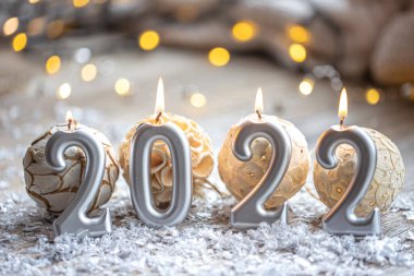 Noel arkaplanı, 2022 sayıları şeklinde mumlar yakarak Bokeh ile bulanık bir arkaplanda kutlanıyor..