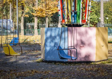 Boş renkli zincirli salıncak sandalyeleri, sonbaharda eski bir lunaparkta atlıkarınca. Geçmiş çocukluk anıları kavramı..