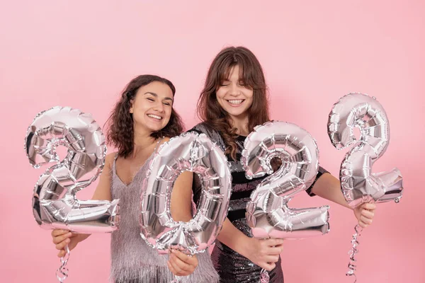 两个女孩在粉色背景下摆出姿势 手里拿着编号2022的银球 — 图库照片