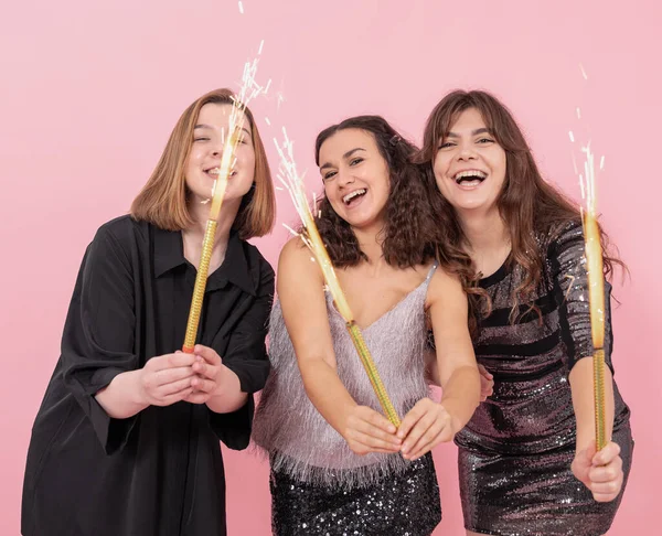 美丽而快乐 穿着粉色背景 点着蜡烛焰火的姑娘们 新年派对的理念 — 图库照片