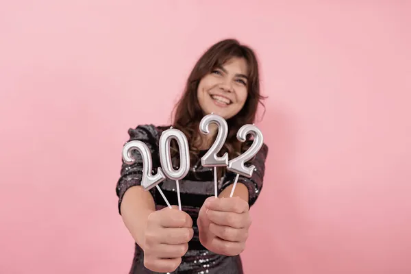 Egy vidám lány rózsaszín háttérrel a kezében tartja a 2022-es számokat.. — Stock Fotó