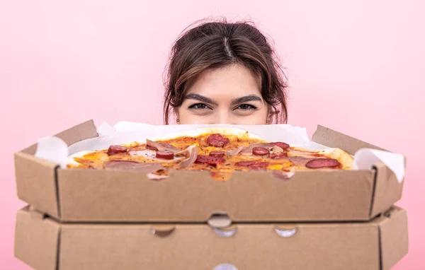 Çekici kız pembe arka planda karton bir kutuda pizza tutuyor.. — Stok fotoğraf