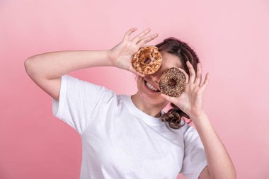 Elinde pembe bir arka planda donut tutan güzel bir kadın..