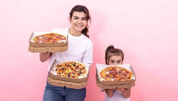 Yetişkin bir kız ve pembe arka planda bir kutu pizzası olan küçük bir kız.. — Stok fotoğraf